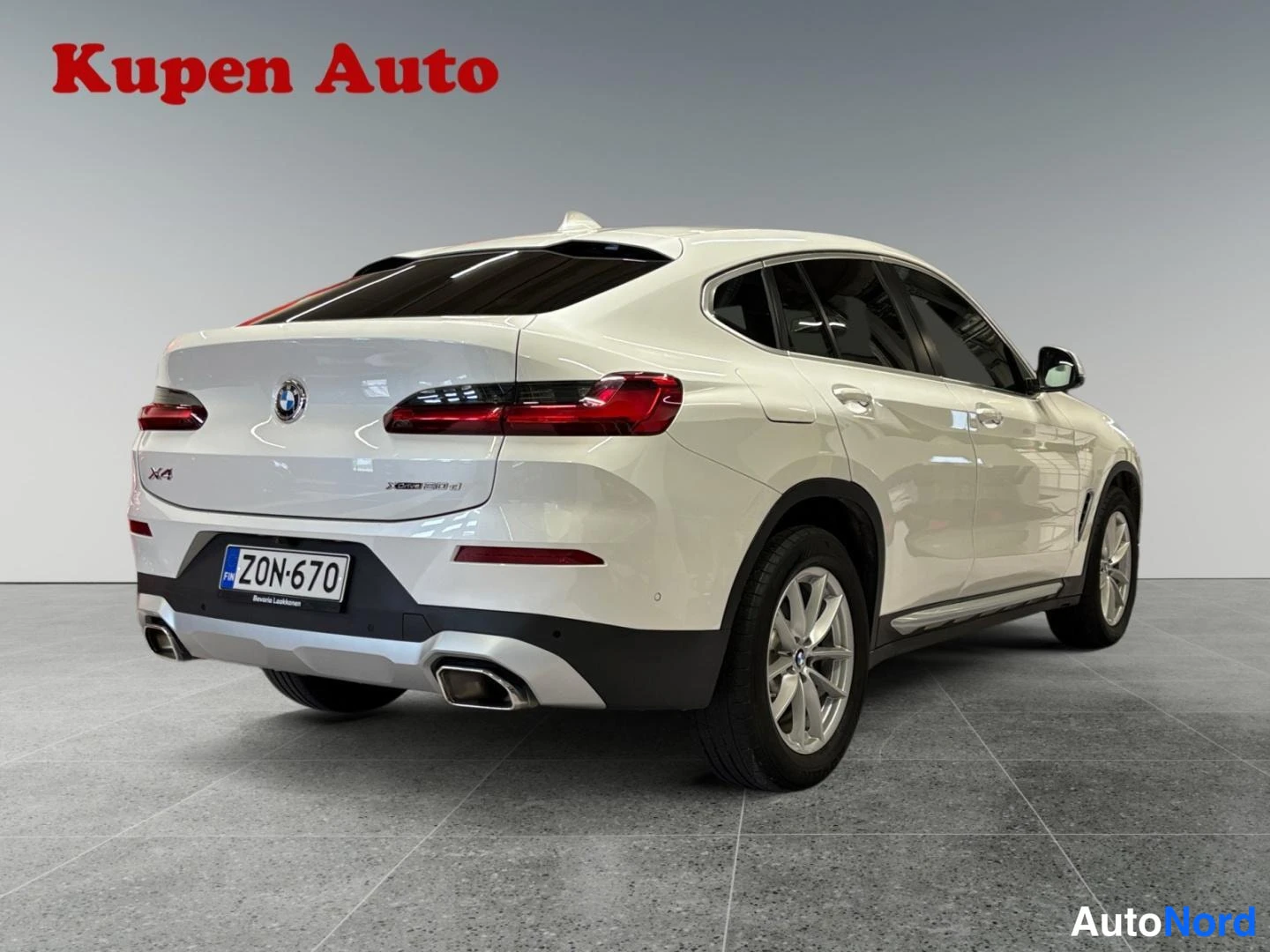 Takaviisto: BMW X4, valkoinen, takakulmakuva vasemmalta, rekisteritunnus, showroom-lattialla