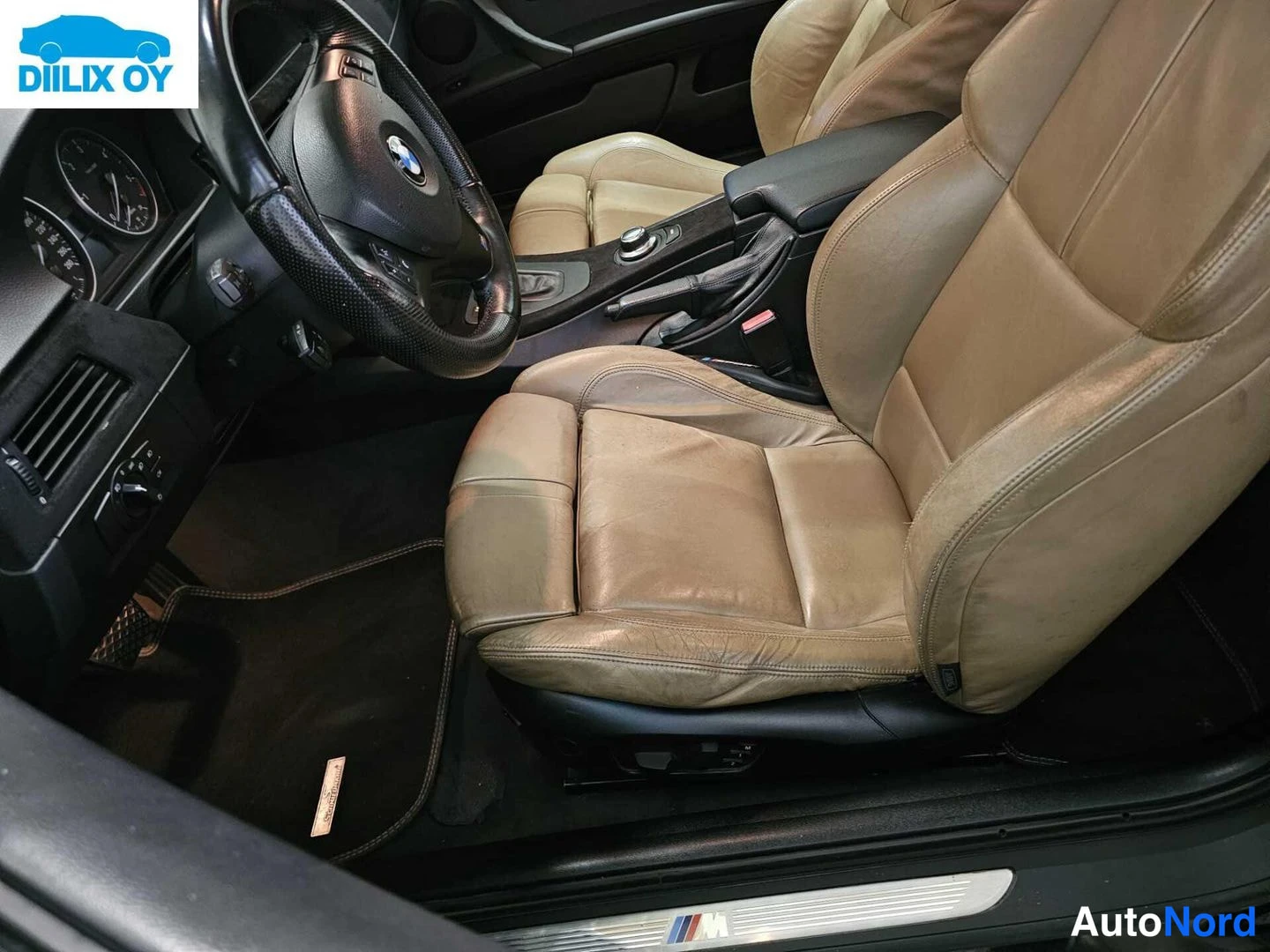 Muu: Ohjaamo kuljettajan puolelta: BMW-ohjauspyörä, beige nahkainen urheiluistuin, automaattivaihteiston valitsin ja M-merkillinen ovikynnyslista.