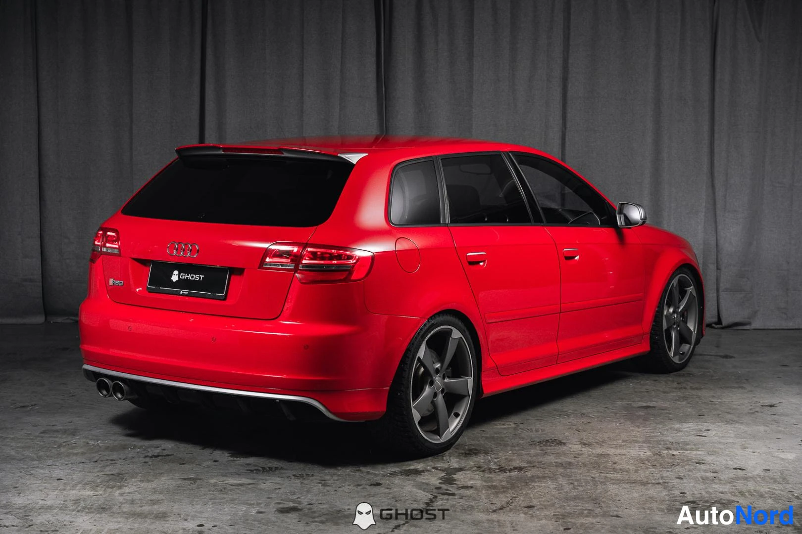 Takaviisto: Punainen Audi A3 Sportback takaviistosta oikealta, kaksoispakoputket ja GHOST-kyltti näkyvät.