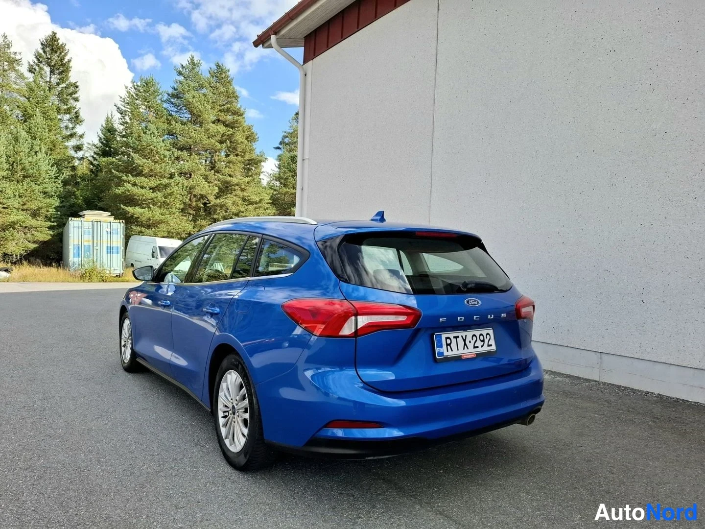 Takaviisto: Sininen Ford Focus -farmari takakulmanäkymä, rekisterikilpi, Focus-teksti ja takavalot näkyvissä.