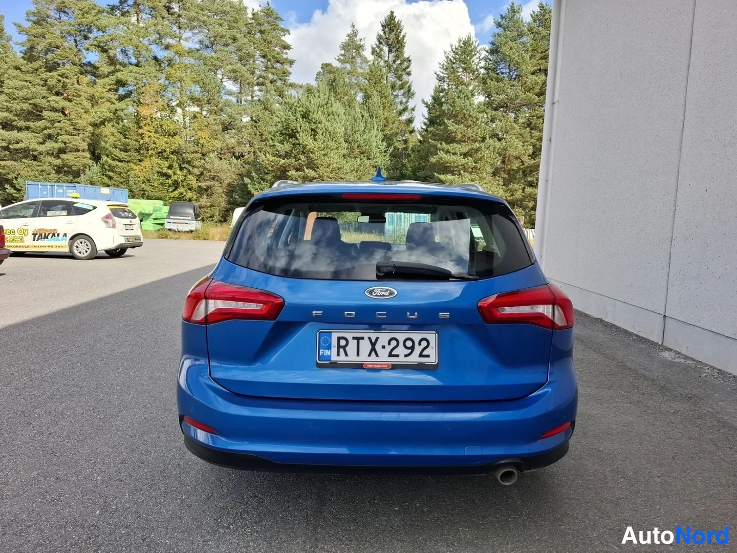 Takaa: Sinisen Ford Focus -farmariauton takaosa suoraan takaa kuvattuna, FOCUS-teksti ja rekisterikilpi.
