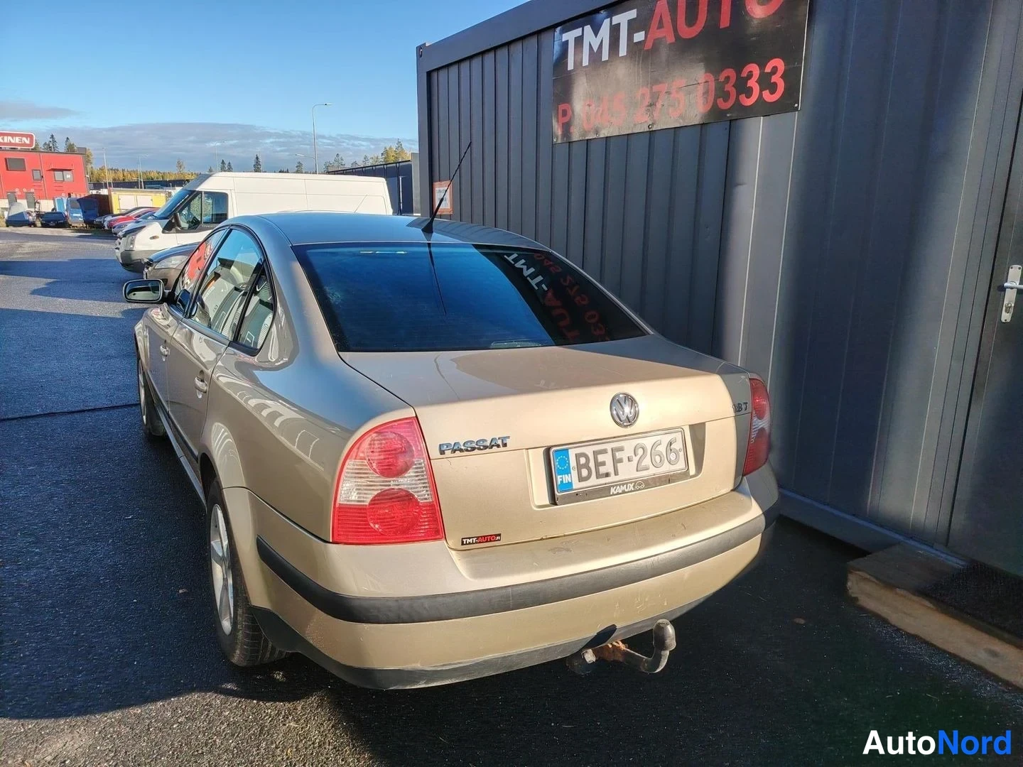 Takaviisto: Volkswagen Passat -sedanin takaosa vasemmalta kulmasta, kulta-beige runko, rekisteri.