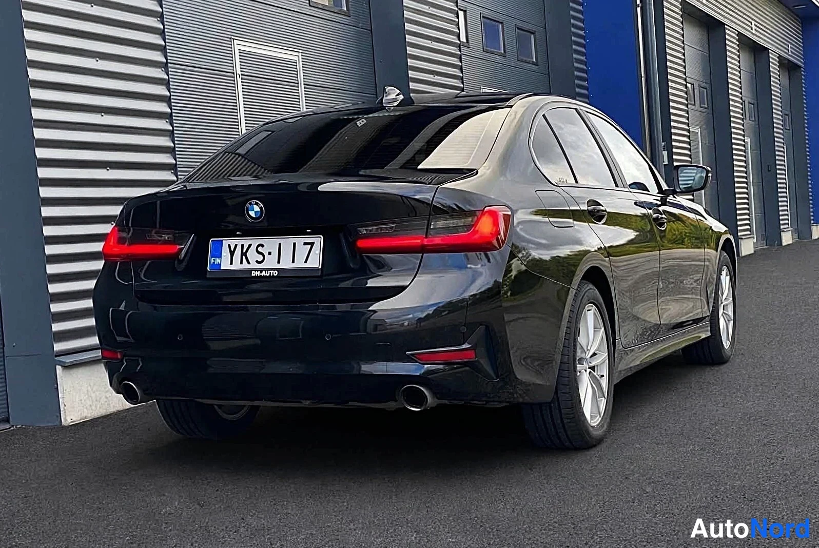Takaviisto: Musta BMW-sedan takaa oikealta kolmesta neljäsosaan, perä vasemmalla, rekisteritunnus.