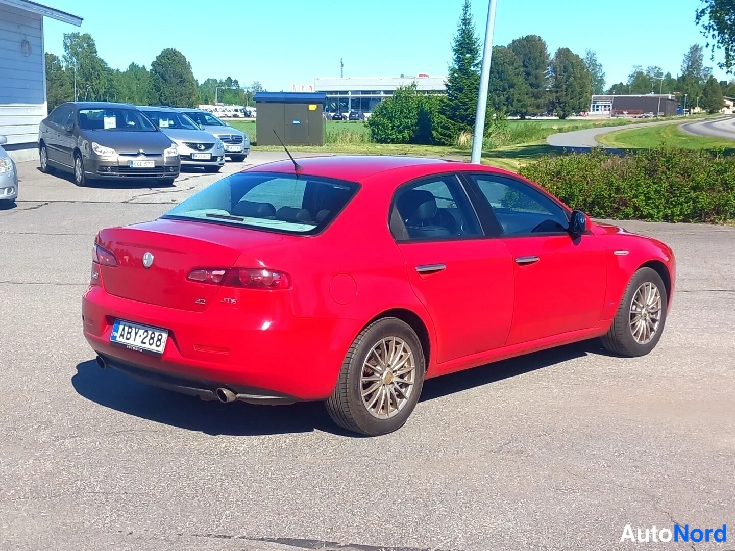 Takaviisto: Punainen Alfa Romeo 159 -sedan takaokoliskuva, rekisteritunnus takapuskurissa.