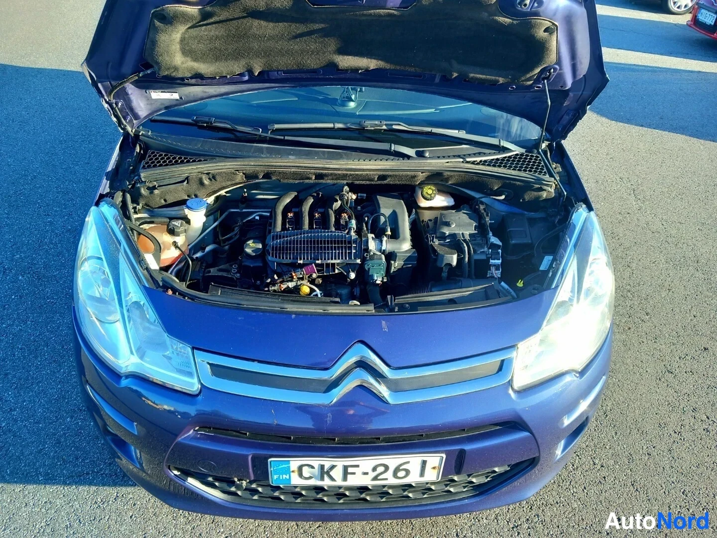 Edestä: Sinisen Citroën C3 -auton avoin konepelti, moottoritila näkyvissä, rekisterikilpi.