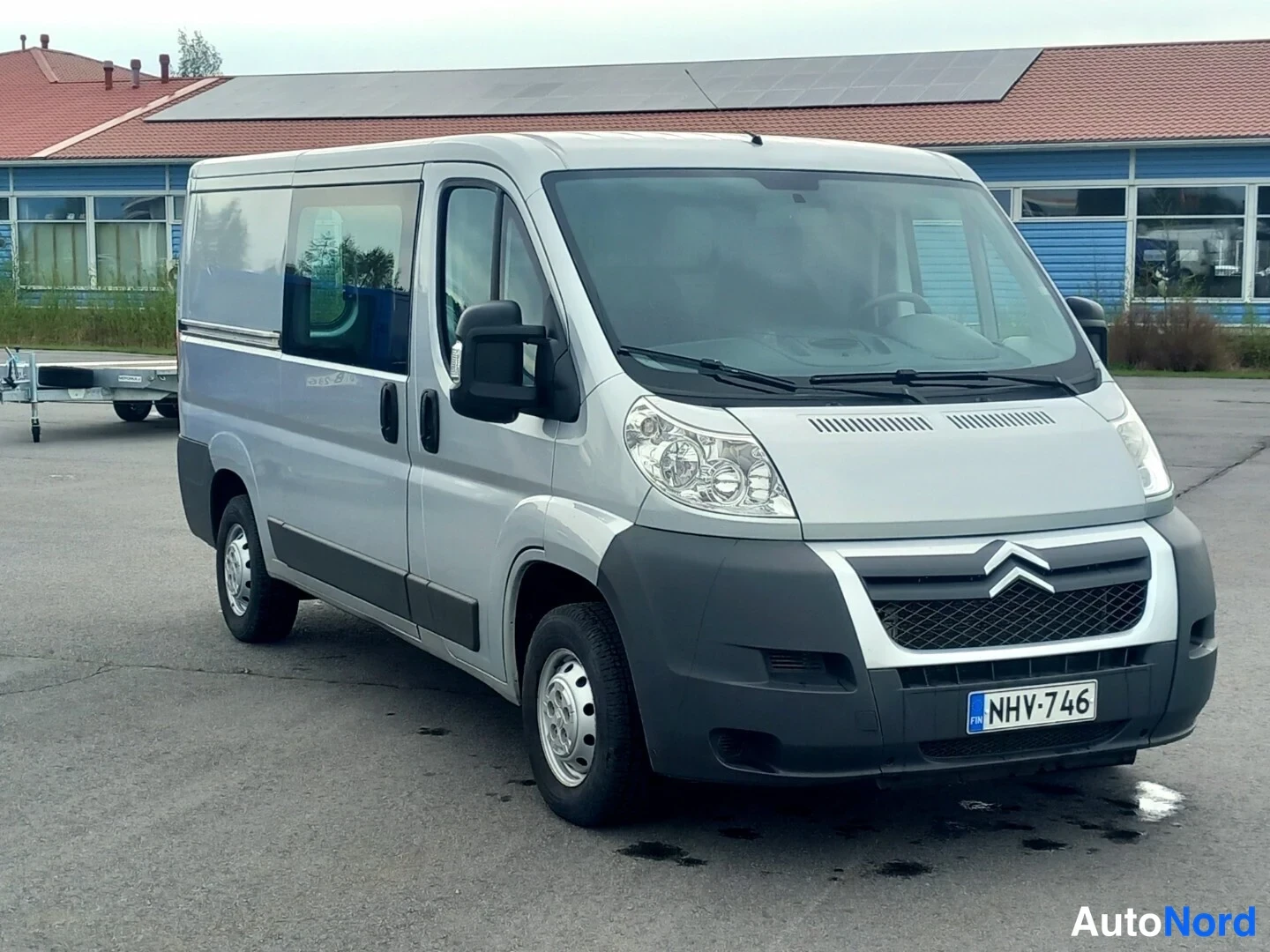 Etuviisto, nokka oikealle: Hopeanharmaa pakettiauto etukulmasta, rekisteritunnus.