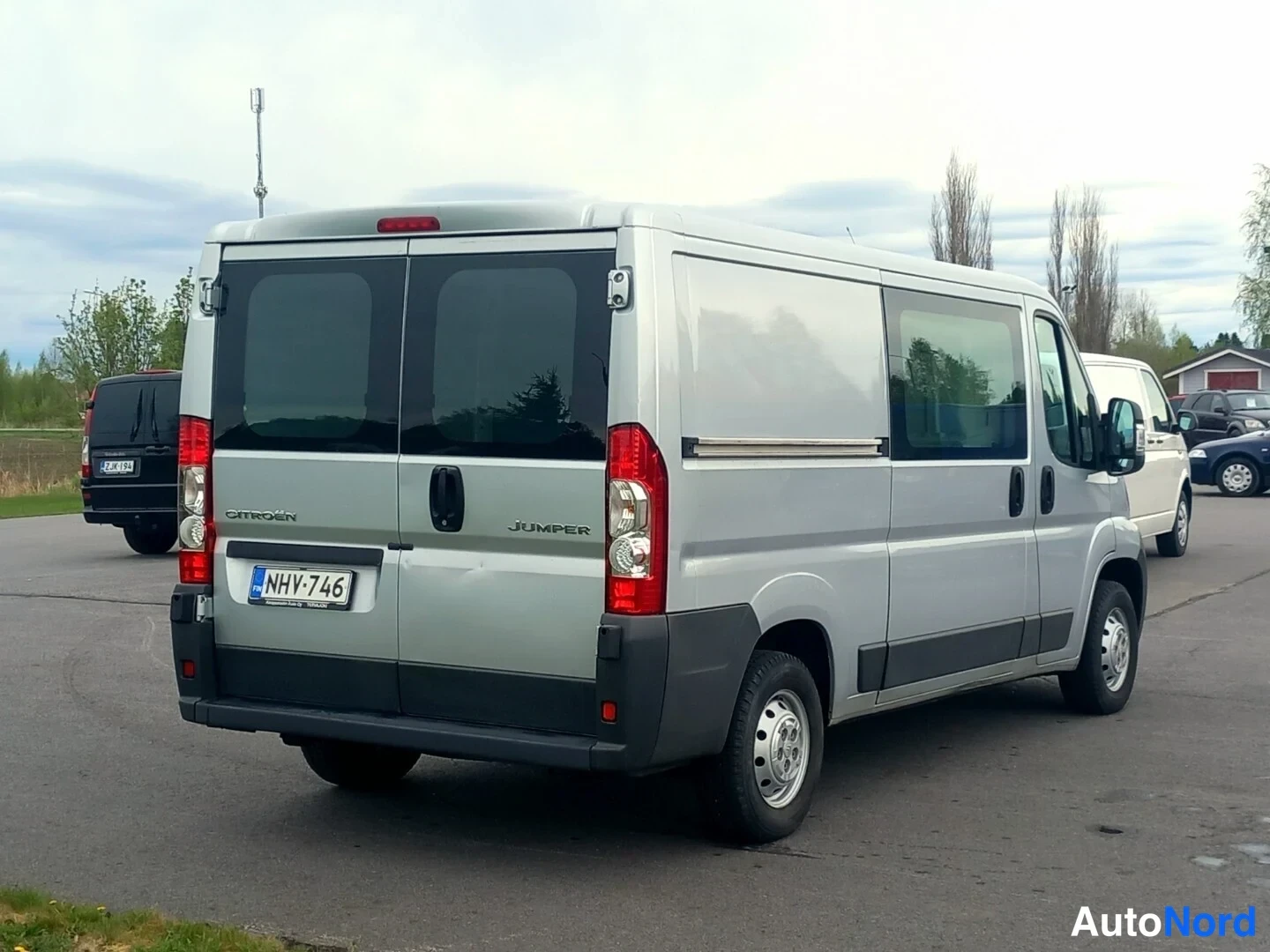 Takaviisto: Citroën Jumper -pakettiauto takaa viistosti vasemmalta kuvattuna, hopeanvärinen kori, sivuovessa kiskollinen varuste.