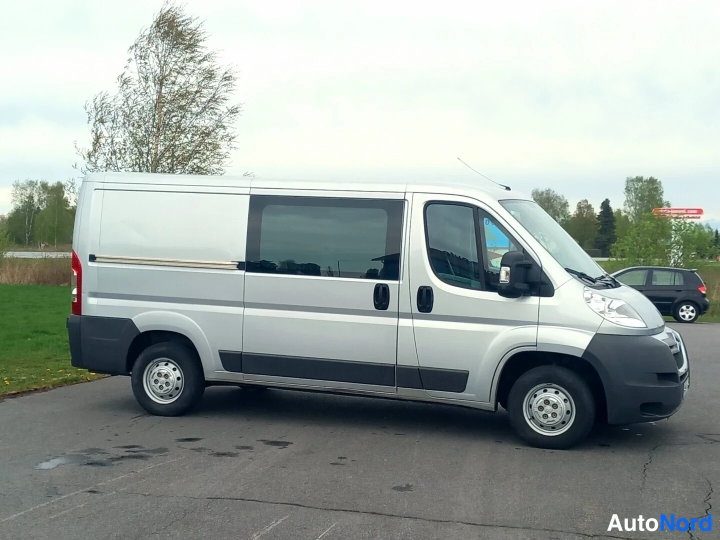 Etuviisto, nokka oikealle: Hopeanvärinen pakettiauto sivulta ja edestä kuvattuna.