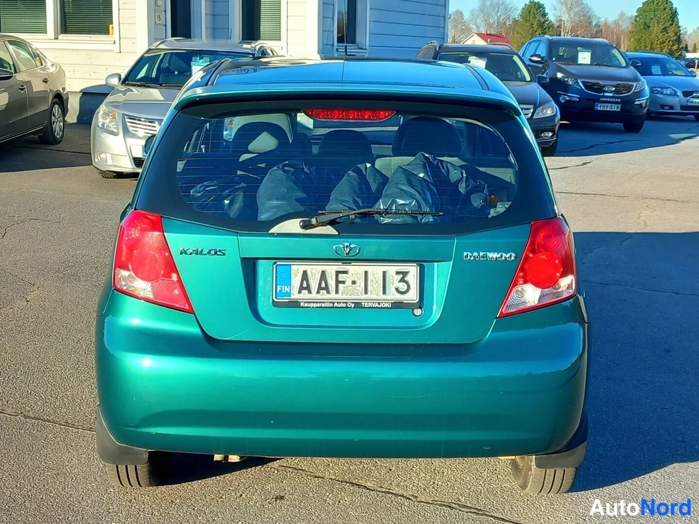 Takaa: Auton takanäkymä: vihreä Koros-pieni, takavalojen välissä Daewoo- ja Kalos-merkit, rekisterikilpi.