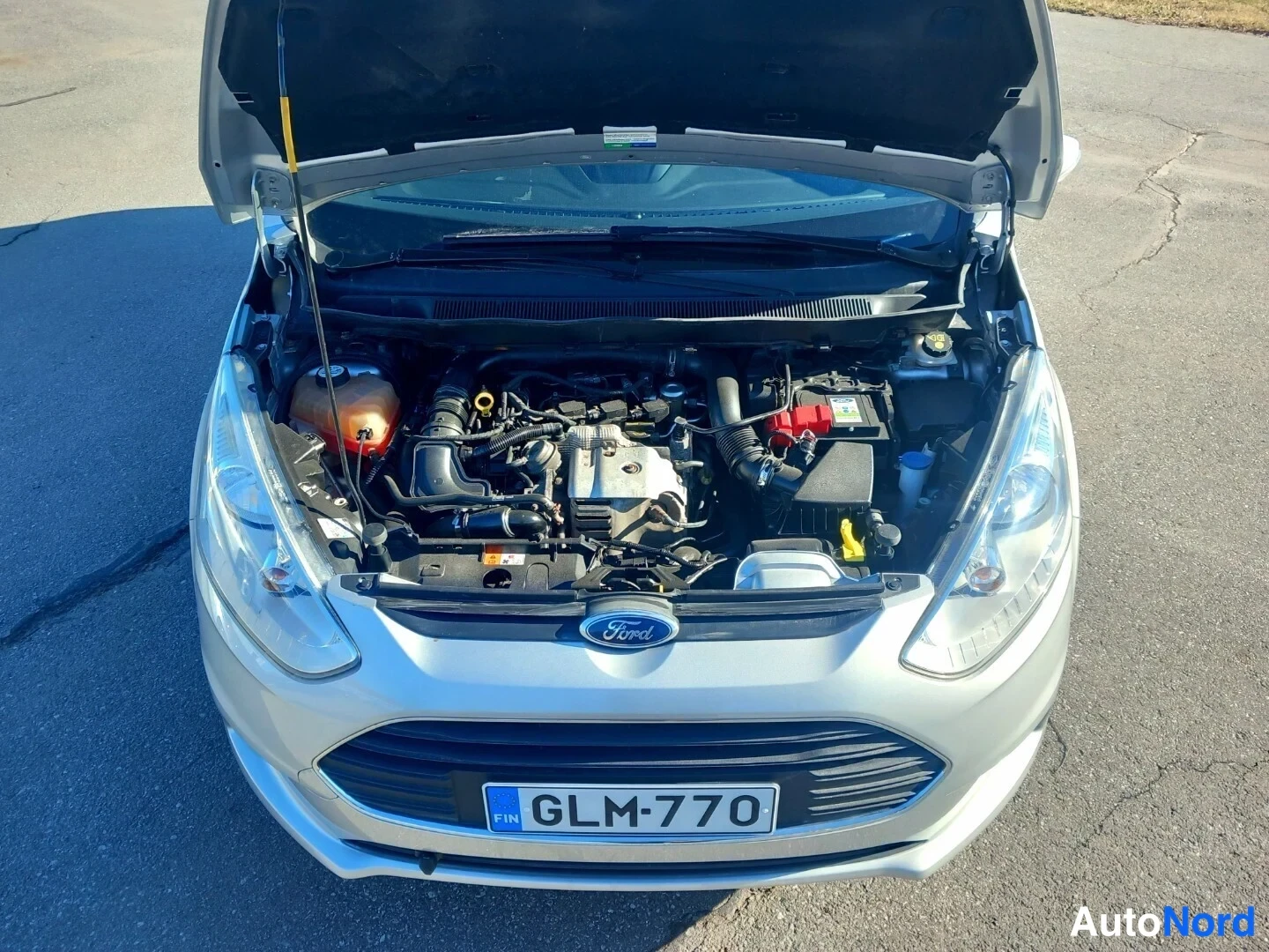 Edestä: Ford B-Max avattu konepelti, moottoritila kuvattuna ylhäältä, rekisterikilpi.