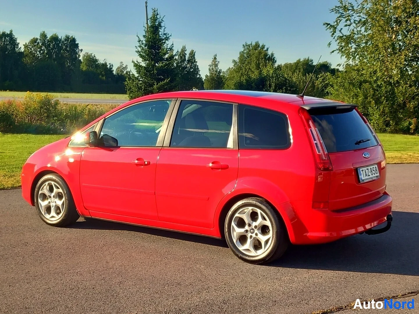Takaviisto: Punainen farmariauto takaviistosta, rekisterikilpi, tummat takaikkunat.