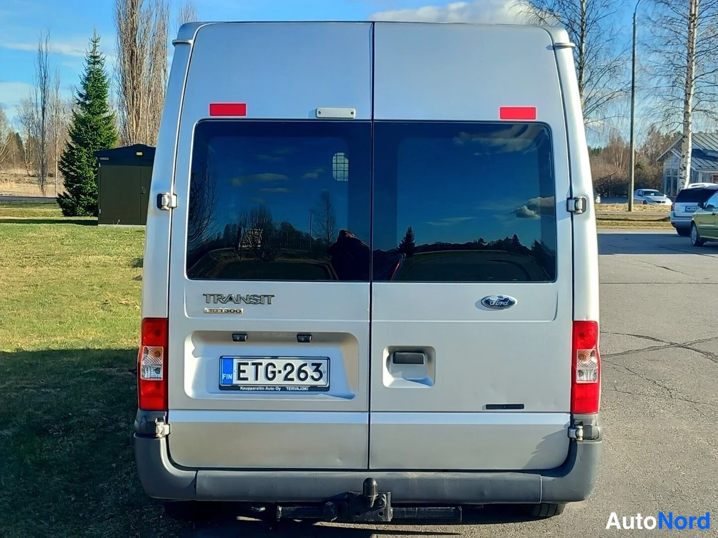 Takaa: Ford Transit -pakettiauto suoraan takaa kuvattuna, takaluukut kiinni, Transit-teksti ja rekisterikilpi.