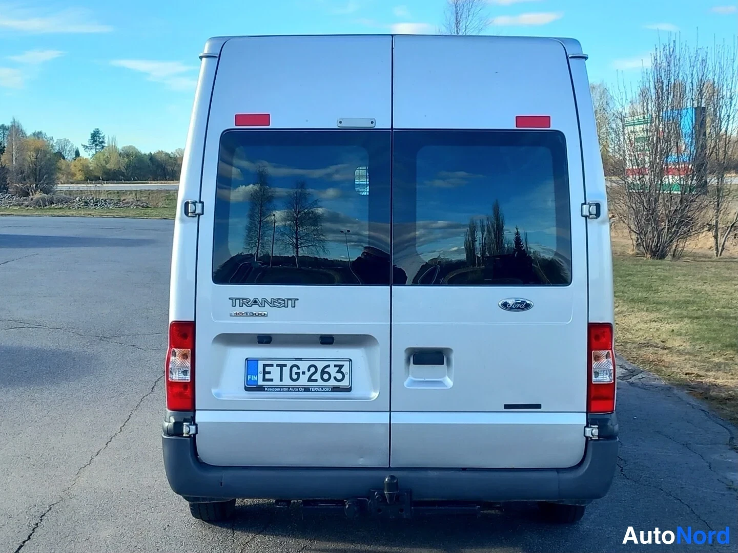 Takaa: Ford Transit -pakettiauton takaosa kadulla, takaluukut, rekisterikilpi ja vetokoukku näkyvissä.