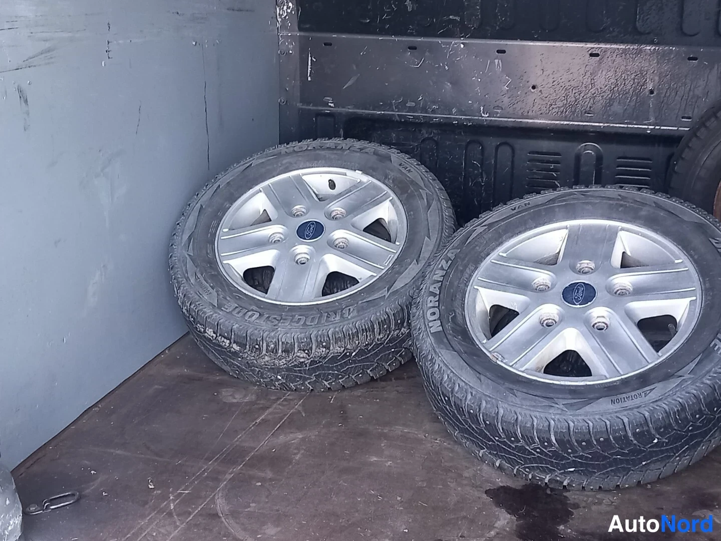 Yksityiskohta: Kaksi talvirenkaita Ford-kevytmetallivanteilla auton tavaratilassa.