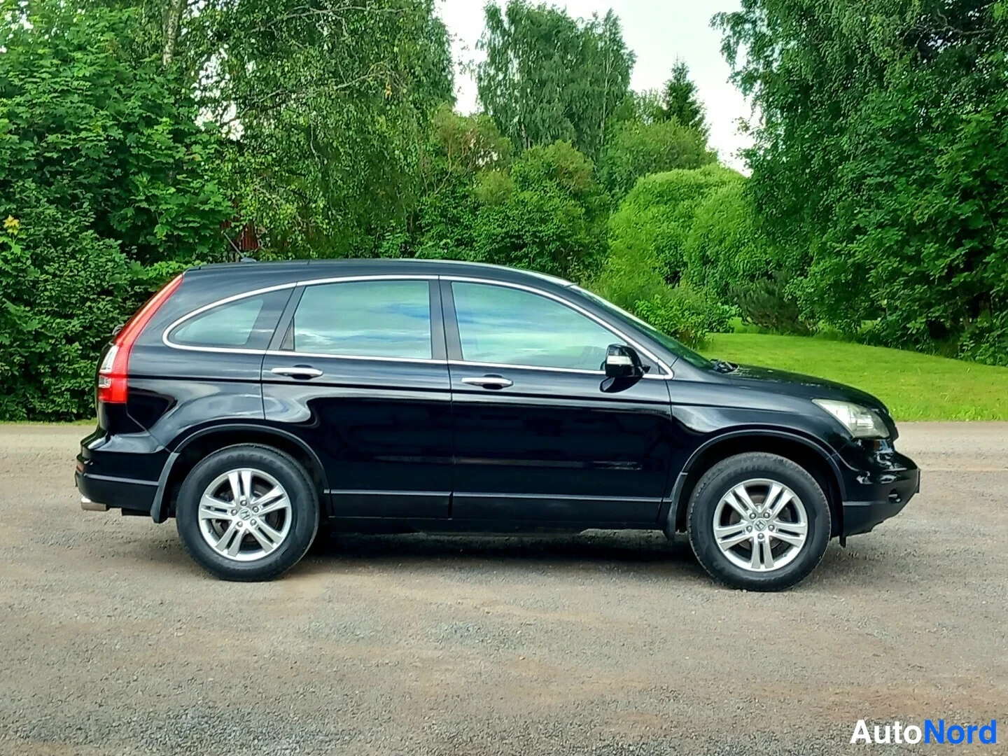 Sivulta: Mustan Honda CR-V:n sivukuva oikealta puolelta, viisiokanta-vanteet ja kromattuja ovenkahvoja.