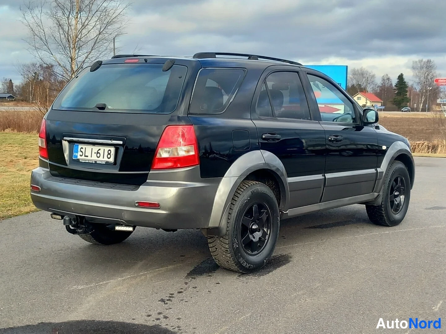 Takaviisto: Mustan Kia Sorenton takaosa ja oikea kylki; näkyvissä takavalot, takapuskuri ja mustat vanteet.