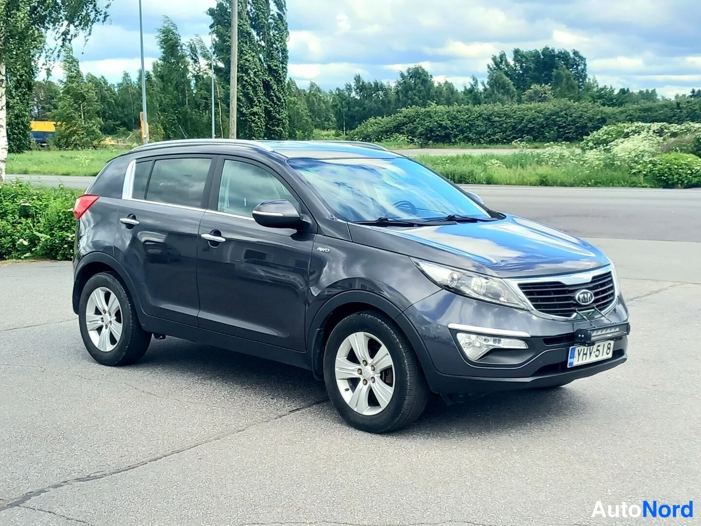 Etuviisto: Tummanharmaa Kia Sportage -maasturin etukulma vasemmalta; näkyvät etusäleikkö, ajovalot, kylki ja rekisterikilpi.