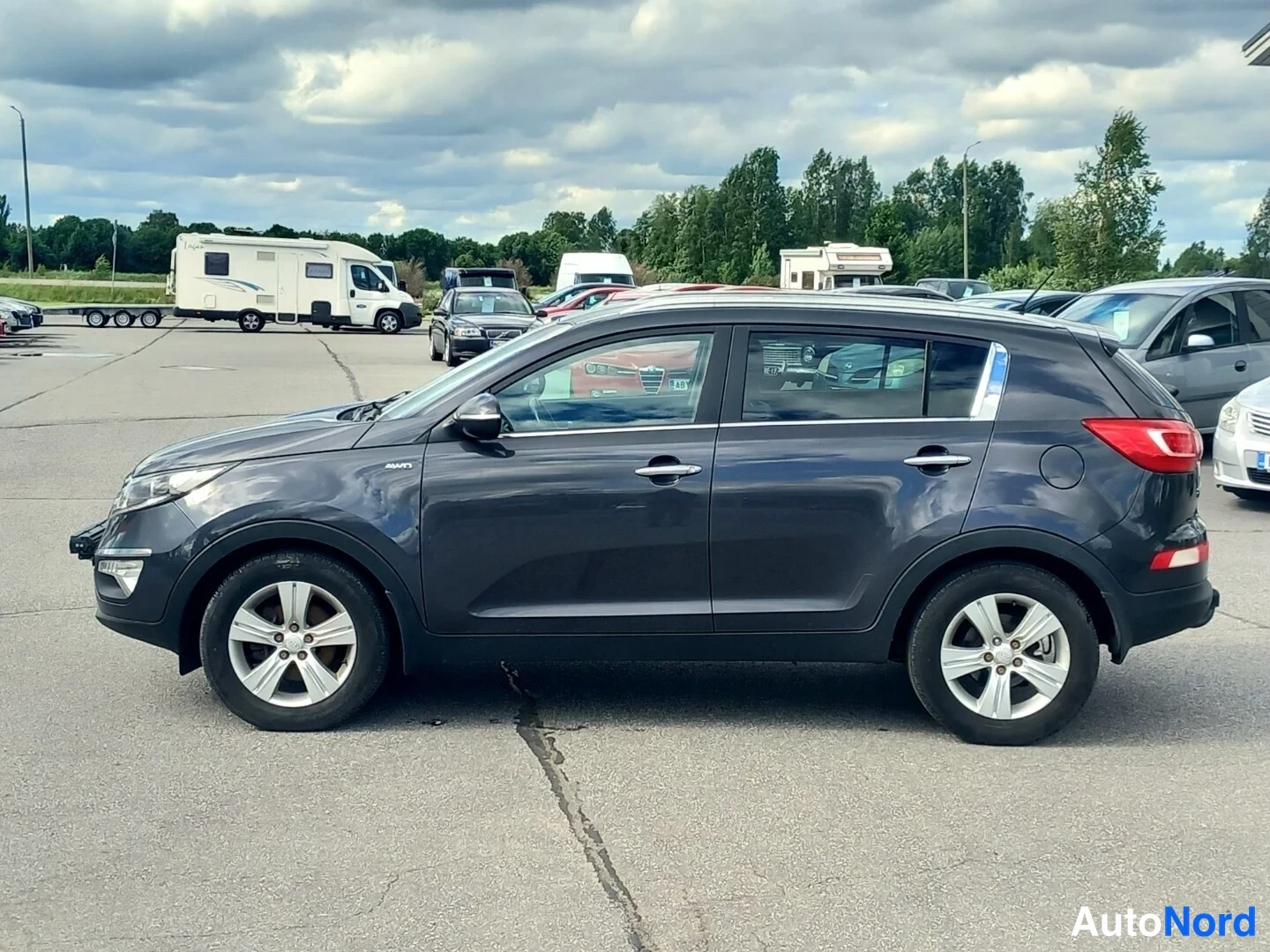 Etuviisto: Kia Sportage edestä vasemmasta kulmasta; ajovalot ja etusäleikkö sekä vasen kylki kuvassa, muiden ajoneuvojen peitykset kyljessä.