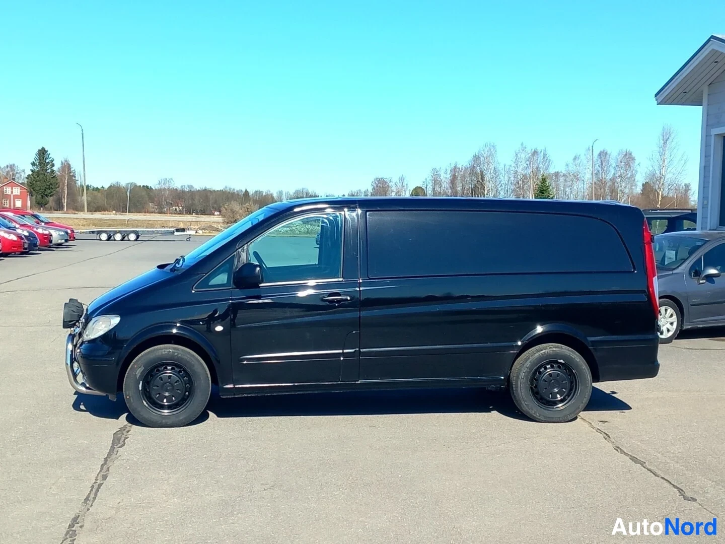 Etuviisto, nokka vasemmalle: Musta Mercedes-Benz Vito -pakettiauto sivulta, keulakoriste ja tummat peltipyörät näkyvät.