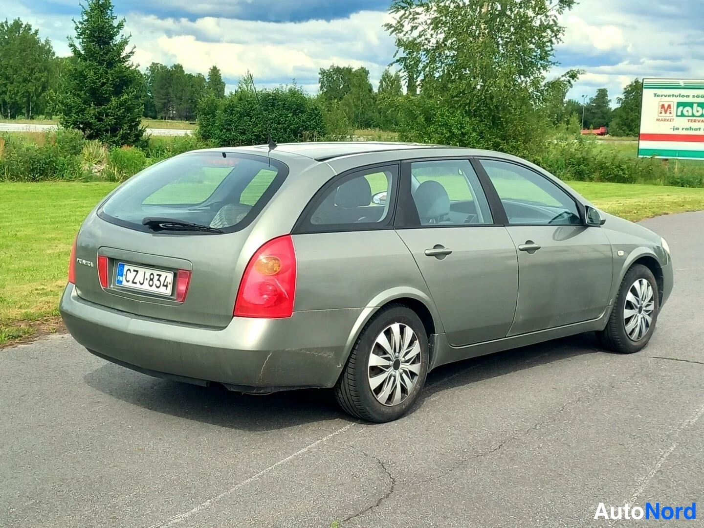 Takaviisto: Nissan Primera -farmari takaviistosta vasemmalta, rekisterikilpi.
