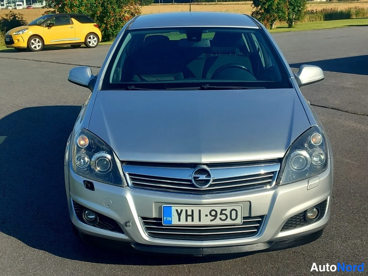 Edestä: Auto suoraan edestä kuvattuna, Opel-merkki kyltissä, rekisterikilpi, hopeanvärinen kori.