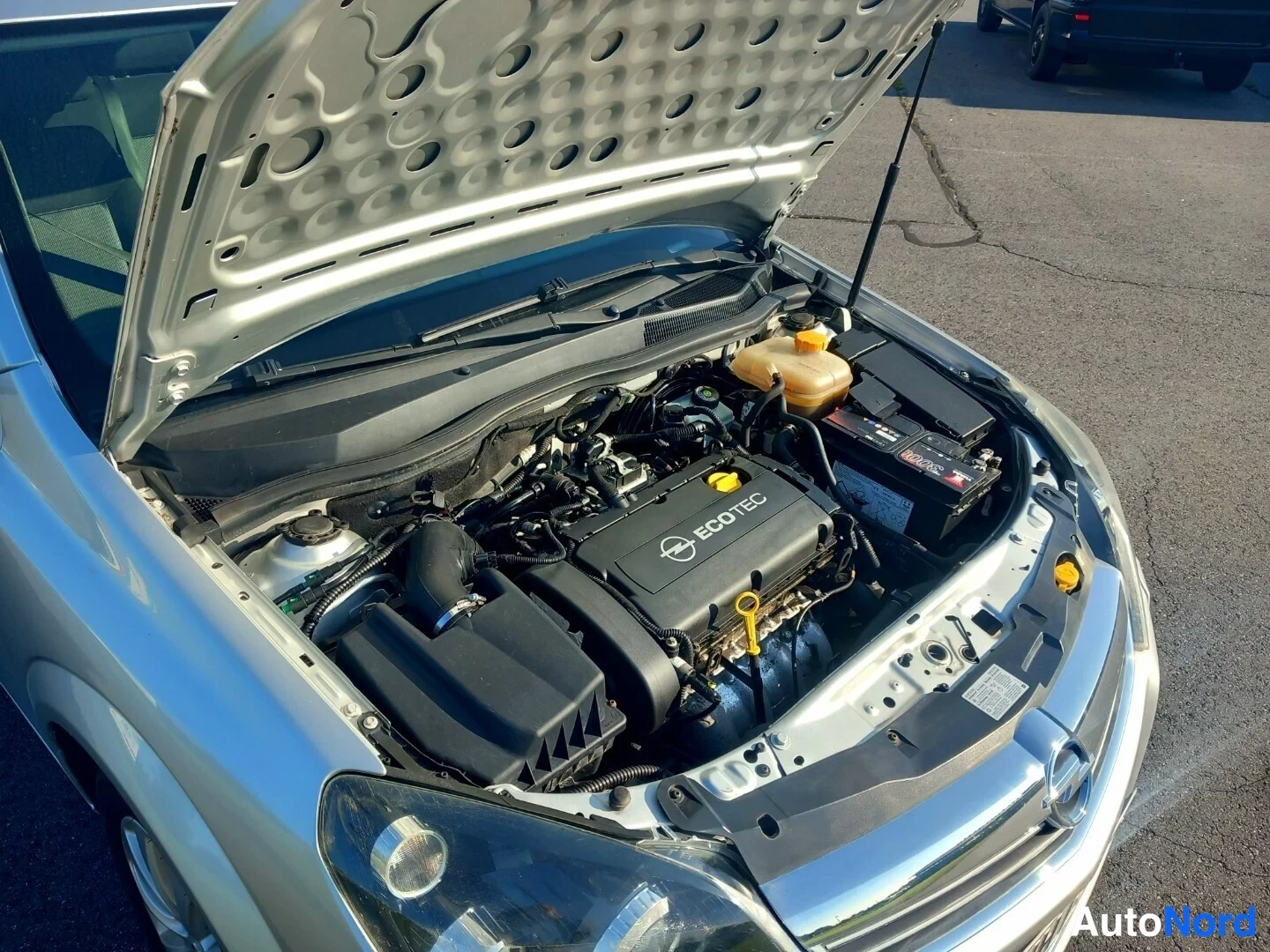 Edestä: Avattu konepelti, Opel-moottoritilassa ECOTEC-kate ja akku.