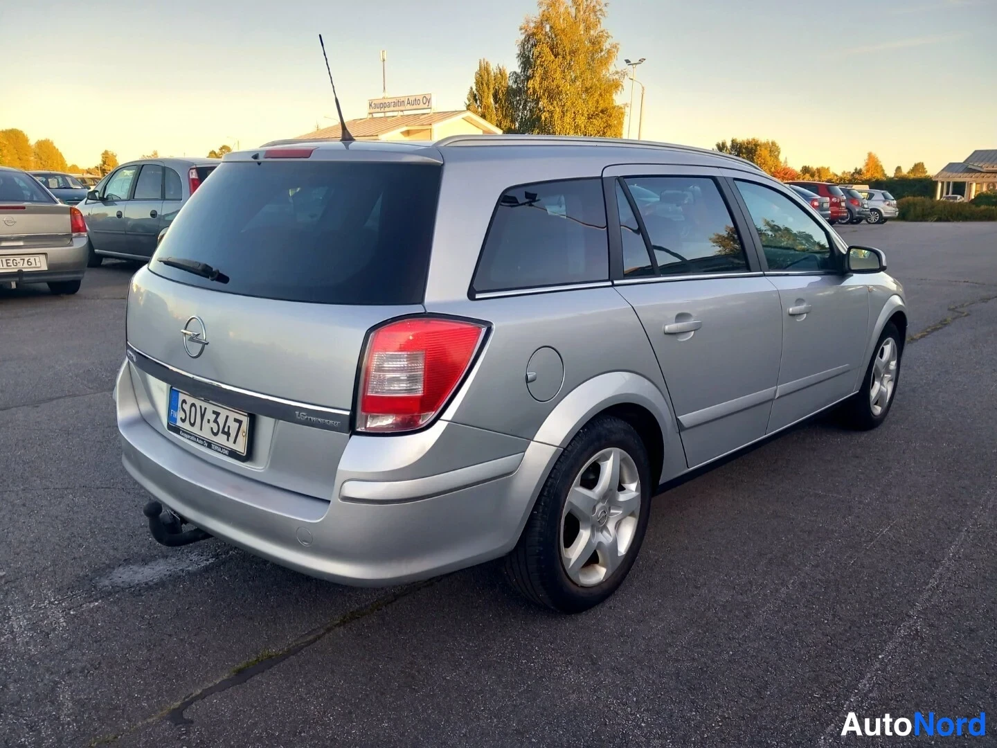 Takaviisto: Hopeanvärinen Opel Astra -farmari takaa oikeasta kolmannesta kuvakulmasta parkkipaikalla, rekisterikilpi ja lisävalo.