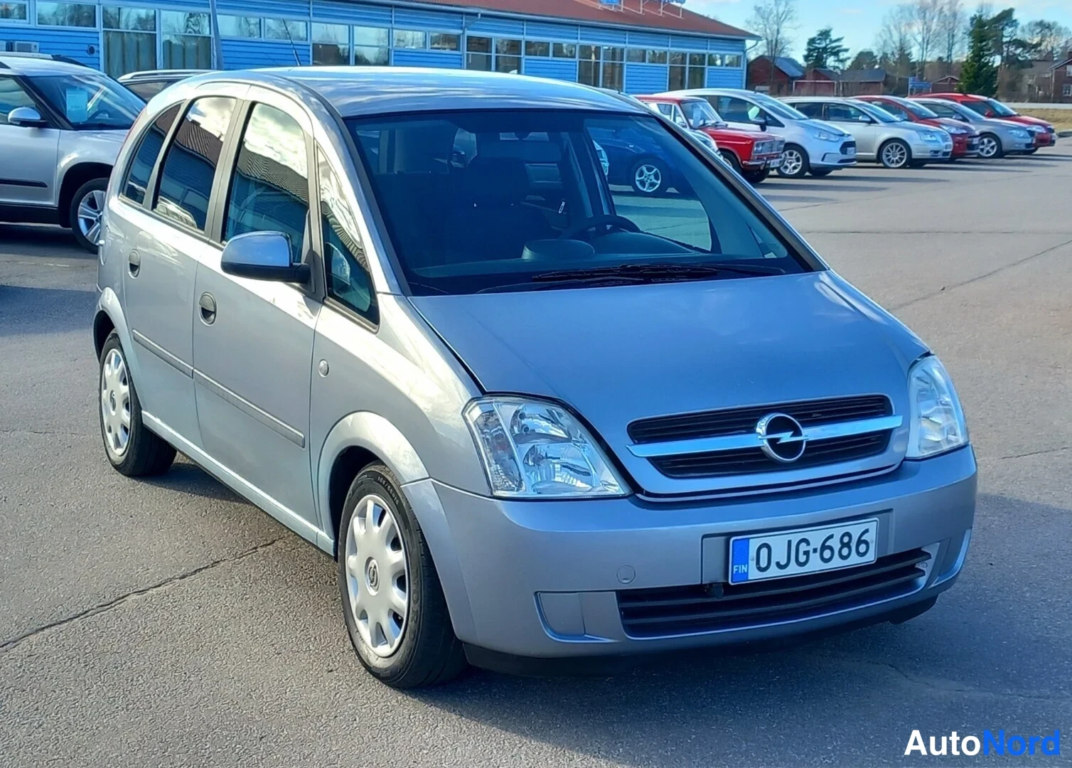 Etuviisto, nokka oikealle: Hopeanharmaa Opel Meriva edessä ja sivulta, rekisterikilpi.