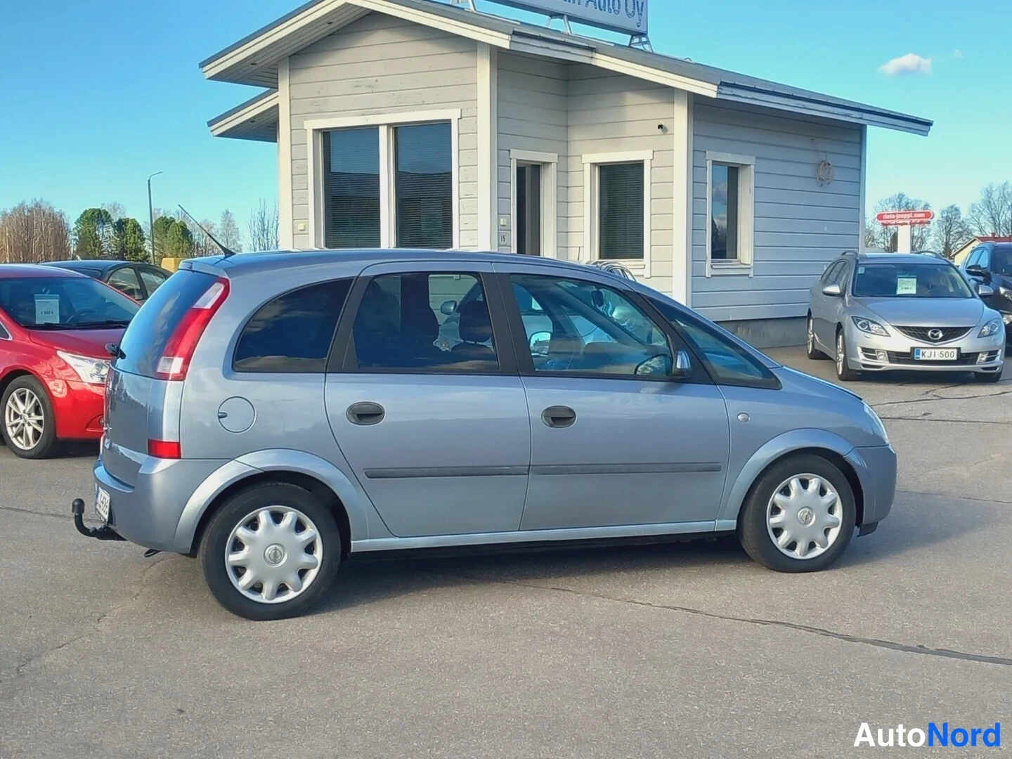 Etuviisto, nokka oikealle: Opel Meriva -auton etukulmakuva oikealta, etuvalo ja kylki näkyvissä, hopeinen koriväri.