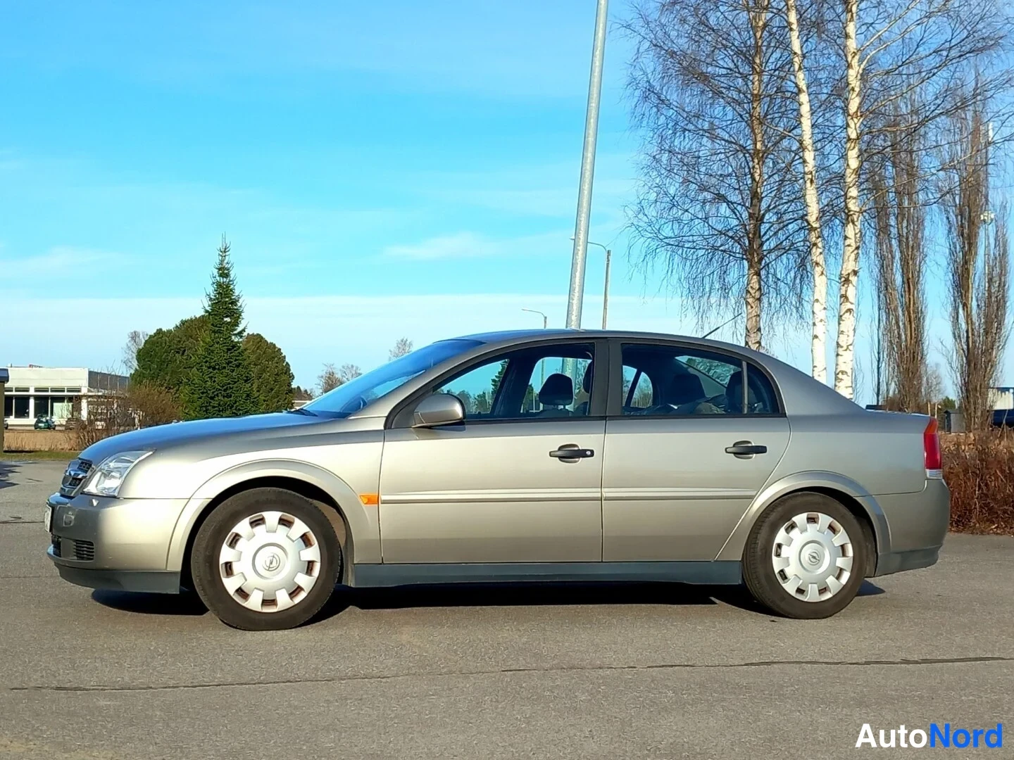 Etuviisto, nokka vasemmalle: Beige Opel Vectra -sedan sivulta vasemmasta etukulmasta tyhjällä parkkipaikalla.