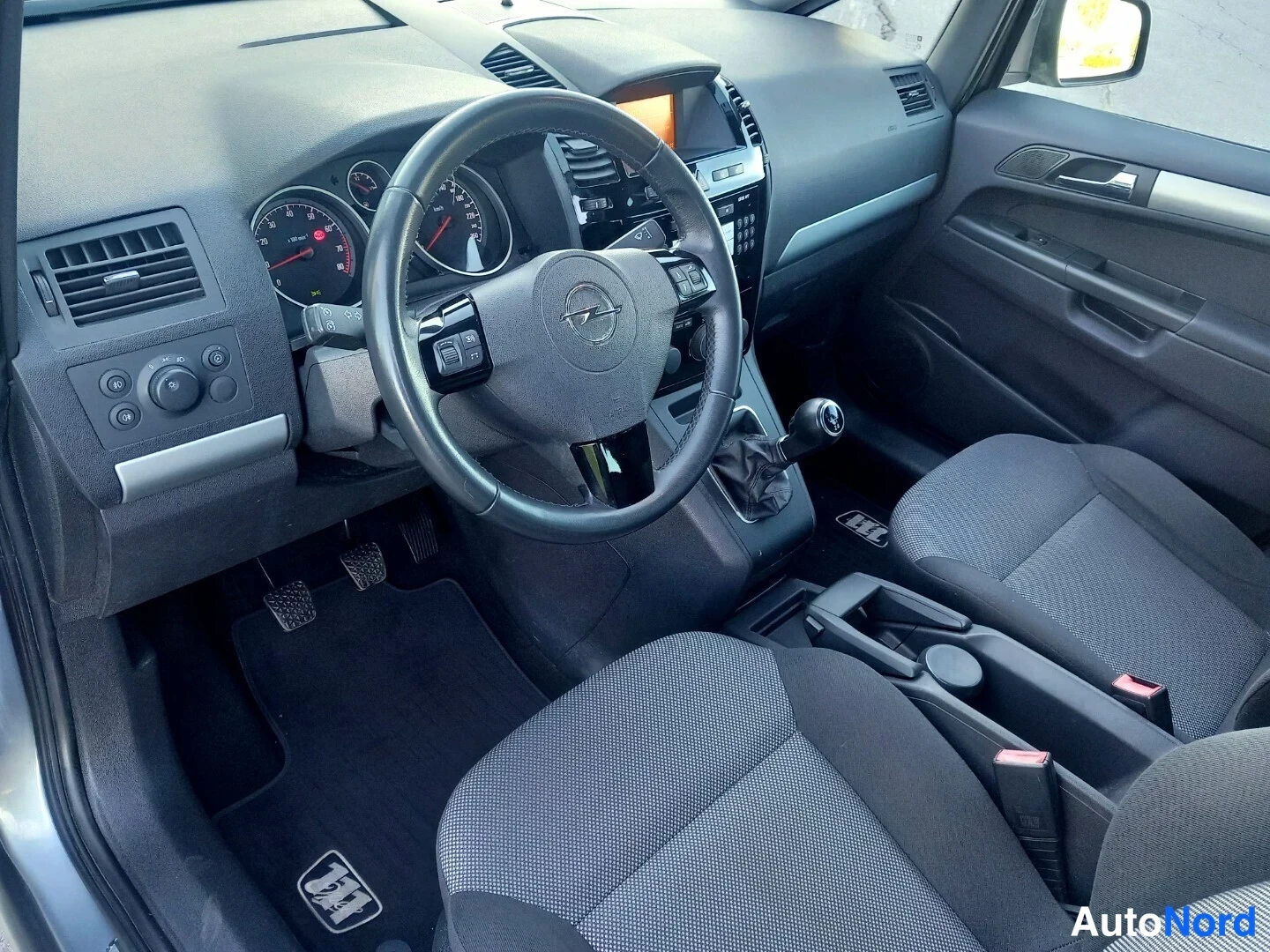 Muu: Opel Zafiran ohjaamo vasemmalta: nahkainen monitoimirattu, analogiset mittarit, manuaalivaihde ja tummat kankaitupenkit.