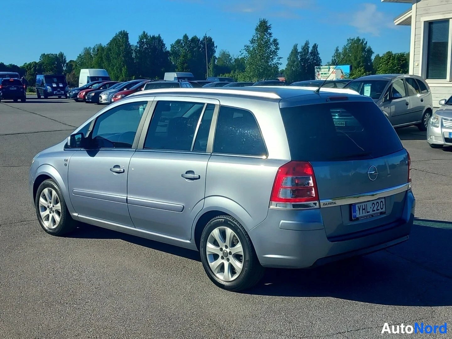 Takaviisto: Hopeanharmaa tila-auto takaa vasemmalta katsottuna, rekisterikilpi.