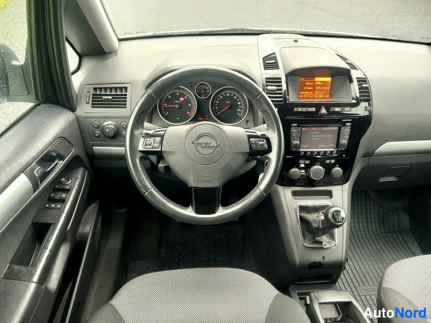 Muu: Ohjaamo Opel Zafirassa: mittaristo, monitoimirattis Opel-logolla, radio ja käsivaihteen vaihtokeppi.