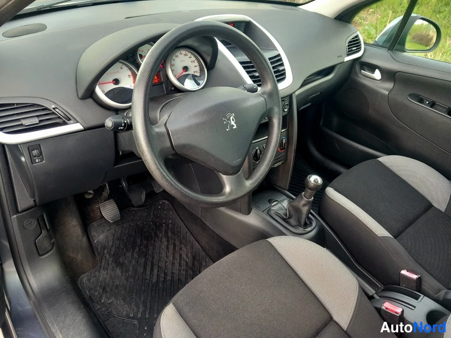 Ohjaamo: Auton ohjaamo: mustat ja harmaat kangasistuimet, manuaalivaihteisto, Peugeot-paalu pyörässä ja mittaristossa, kolme painiketta keskuspaneelissa