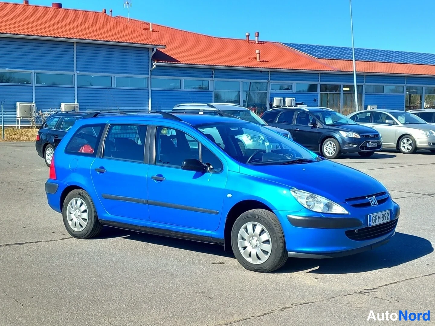 Etuviisto, nokka oikealle: Sininen Peugeot 307 farmari kolmestaneljänneksestä edestä oikealta, rekisteritunnus.