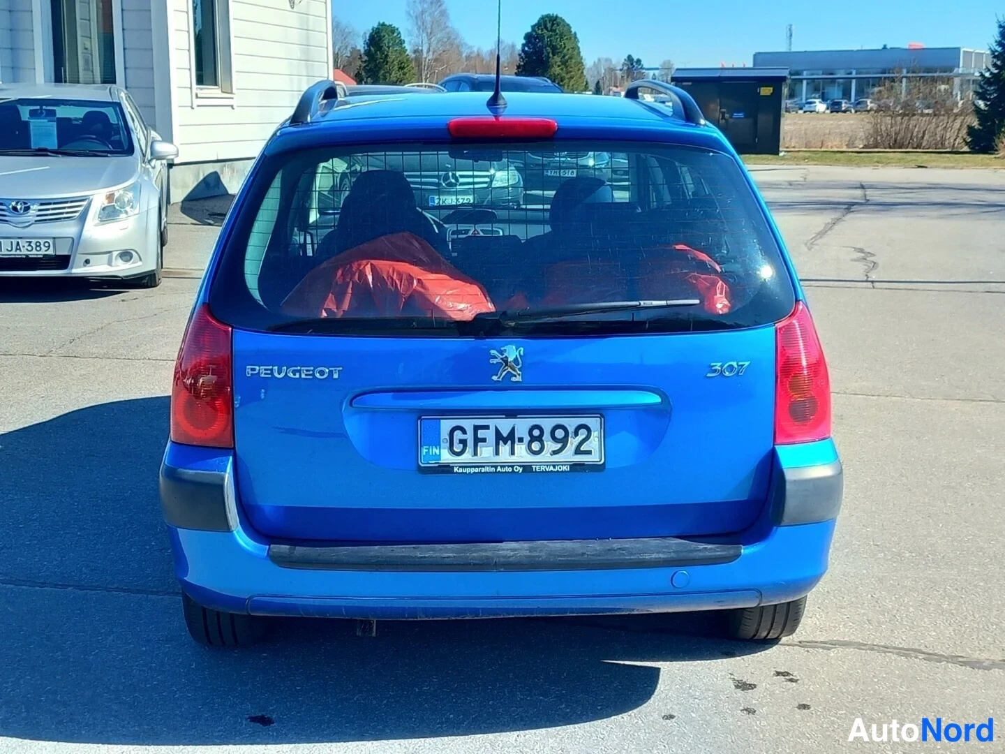 Takaa: Peugeot 307 -farmarin takaosa takaa kuvattuna, merkintä PEUGEOT 307 ja rekisteritunnus, takaikkunassa kuormaverkko.