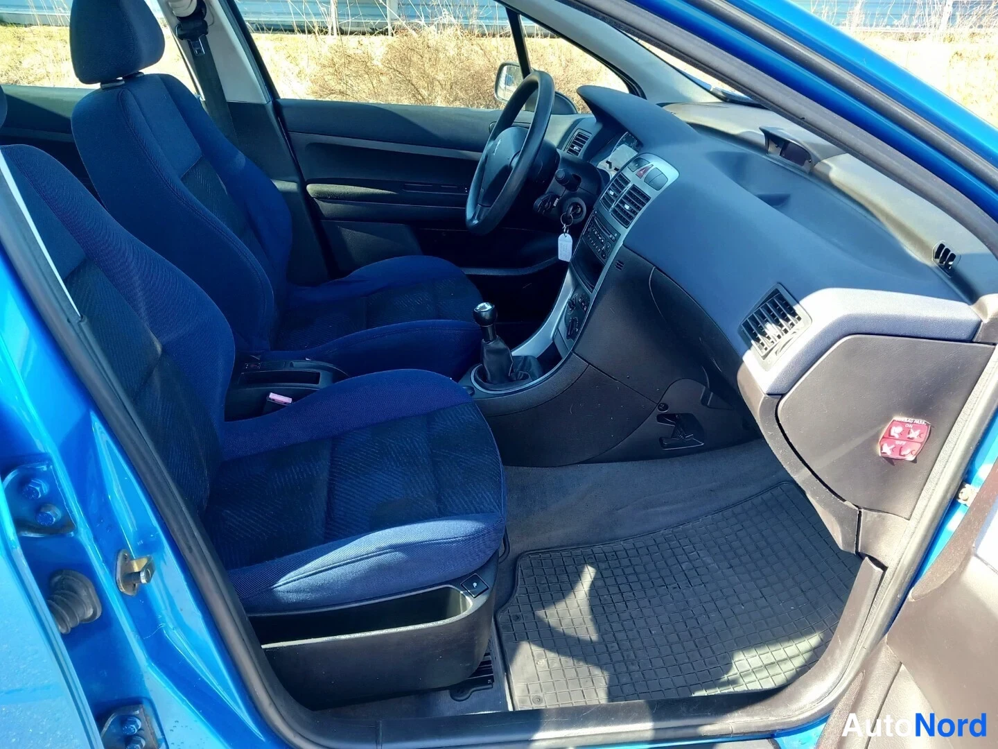 Muu: Peugeot 307:n sisätilat etumatkustamosta: siniset kangasistuimet, ohjauspyörä ja vaihtaja.