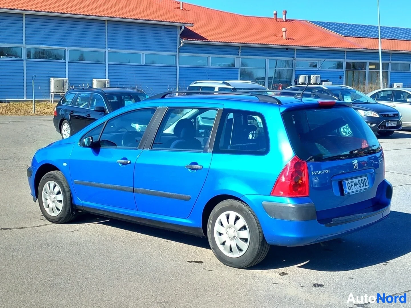 Takaviisto: Sininen Peugeot 307 farmari takaa kolmestaneljänneksestä vasemmalta, rekisteritunnus.
