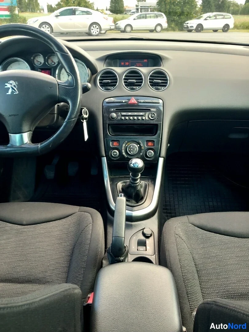 Muu: Ohjaamo näyttää kohti tuulilasia: ohjauspyörä Peugeot-logolla, kolme pyöreää ilmastointisuutinta kojelaudassa, radio ja manuaalivaihteisto keskikonsolissa, kang