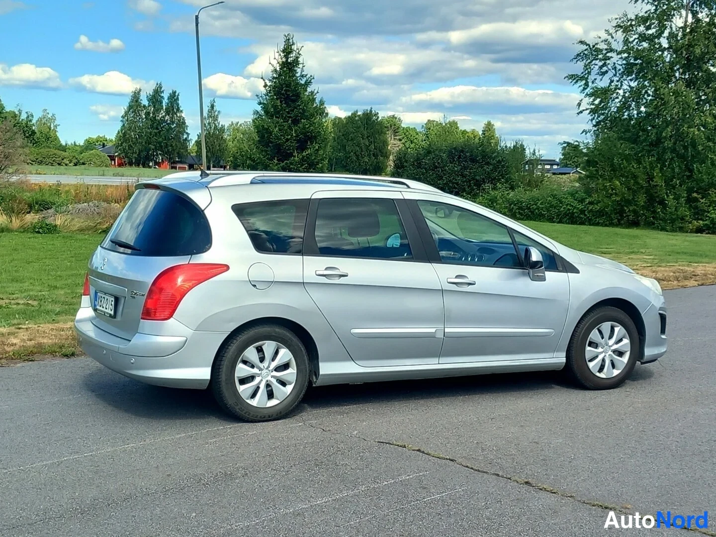 Takaviisto: Hopeanvärinen farmariauto autotallin edustalla, takakulmasta kuvattuna