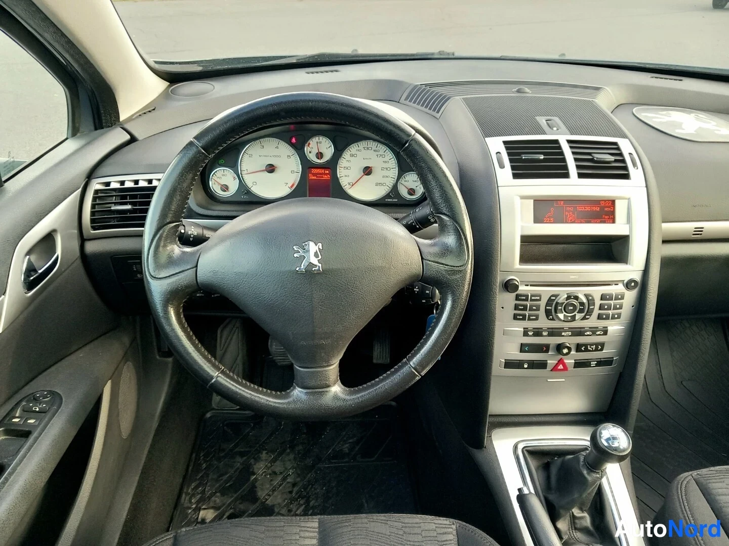 Muu: Peugeot 407: n from the driver's side: steering wheel, instrument cluster, centre console, gear lever, dashboard and windscreen visible, dash slightly dusty.