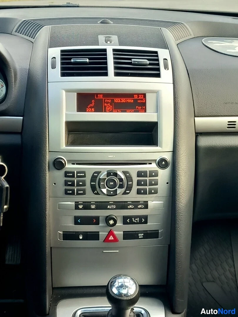 Muu: Sisäkuva auton keskikonsolista: radio-CD-yksikkö, ilmastoinnin AUTO-napit, varoitusmerkin vipu ja automaattivaihteen valitsin.