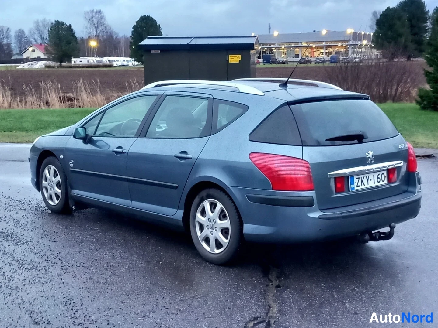 Takaviisto: Peugeot 407 -farmarin takaosa ja kylki vinosti takaa, rekisterikilpi, perävaunukoukku näkyy.
