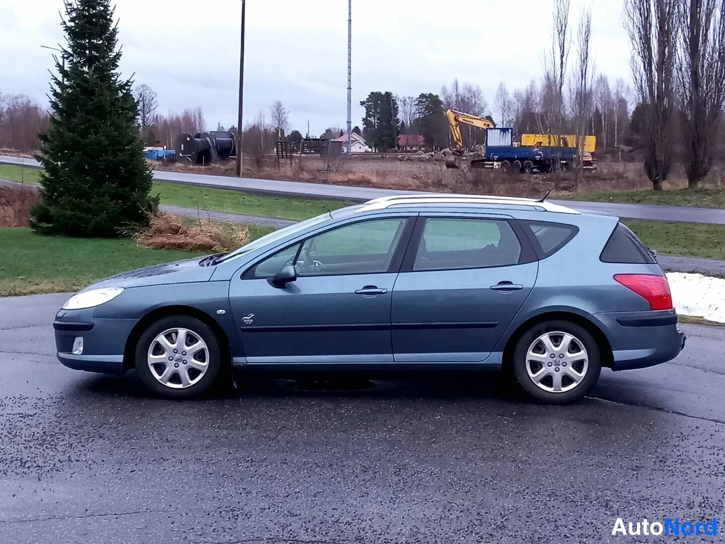 Sivulta: Peugeot 407 -farmarin sivuprofiili oikealta, sinisenharmaa kori, kattokaiteet näkyvät.