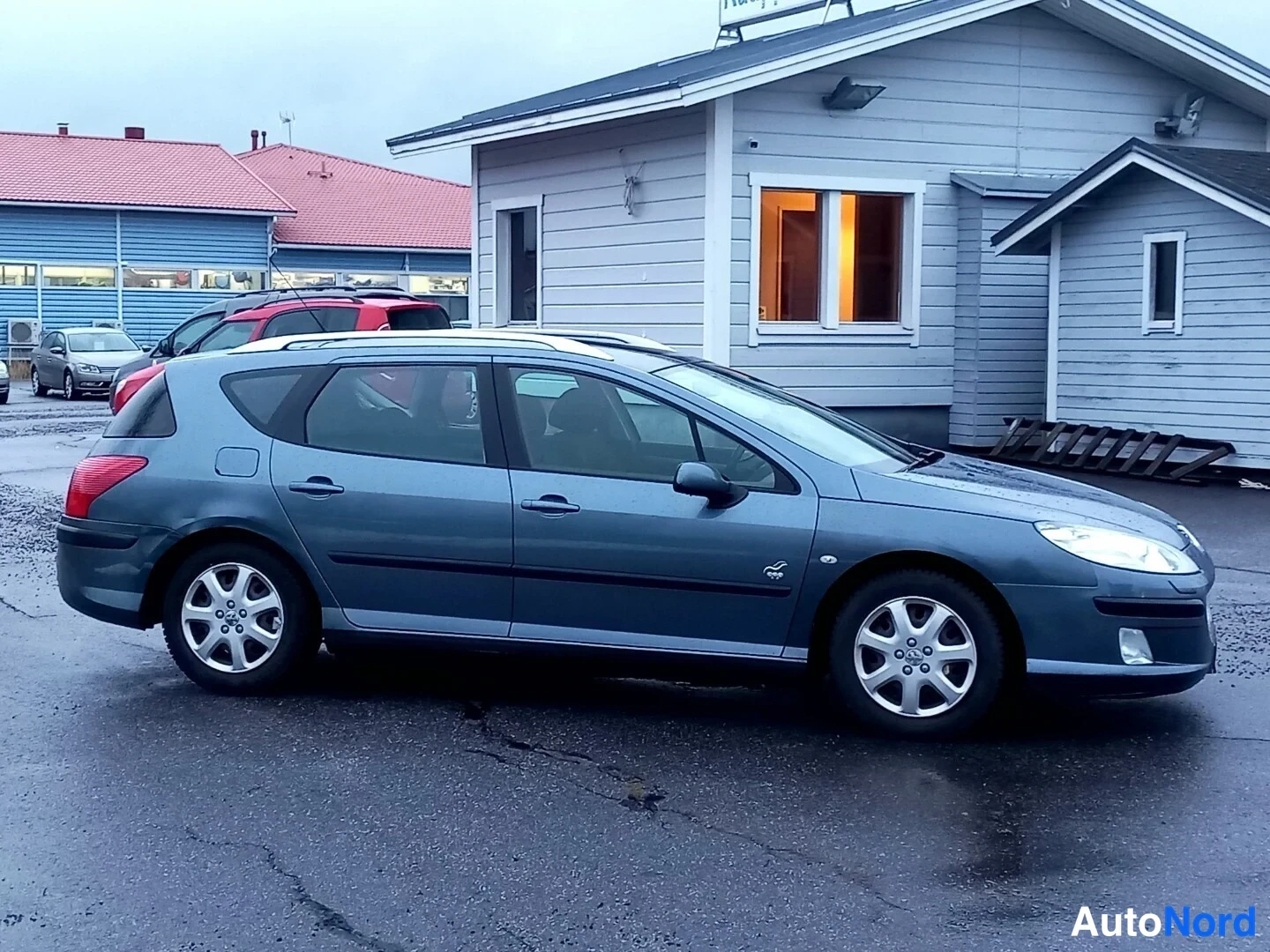 Etuviisto, nokka oikealle: Peugeot 407 -farmariauto kolmineljännestä oikealta edestä, harmaansininen kori.