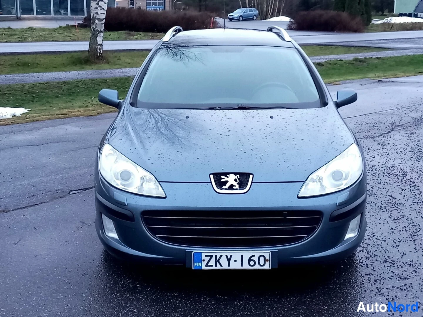 Edestä: Peugeot 407:n keulakuva edestäpäin, rekisteritunnus, harmaansininen kori.