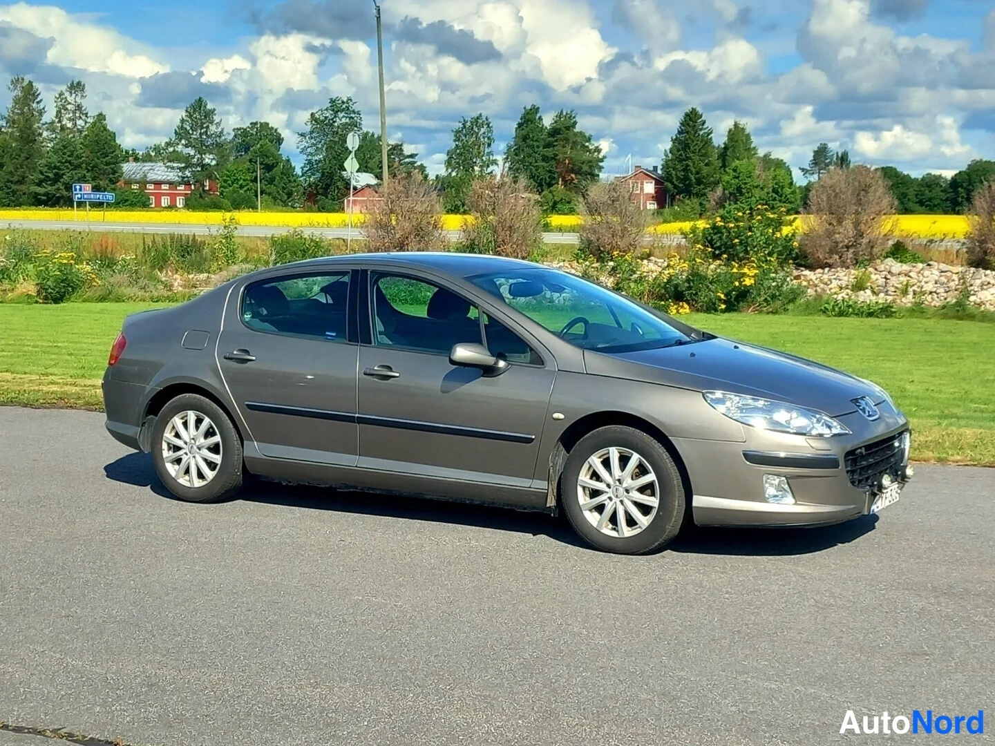 Etuviisto, nokka oikealle: Peugeot 407 -sedan kolmannesvyöristä keulasta oikealle, kokonaisuus näkyvissä pellolla.