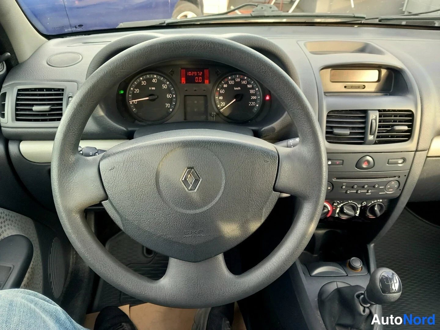 Etuistuimet: Ohjaamon kuva: Renault-ohjauspyörä jossa SRS-AIRBAG teksti, mittaristo osoittaa lukemana 102972 kilometriä (digitaalinen näyttö). Radioyksikkö ja ilmastointiohj