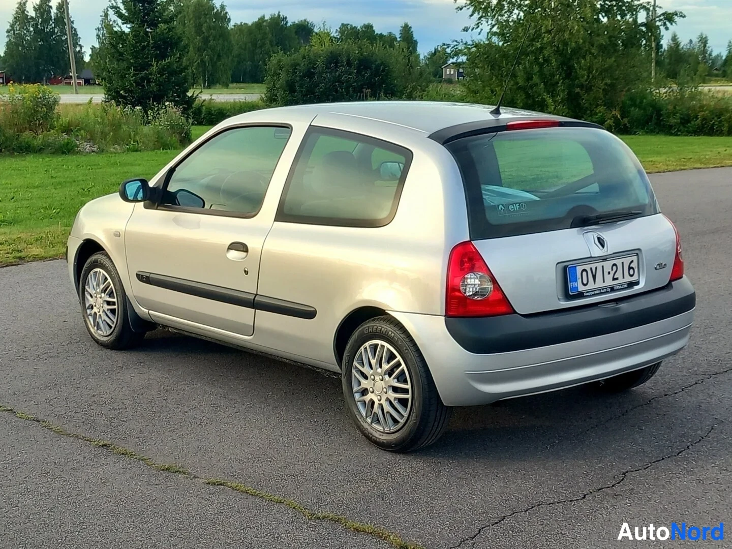 Takaviisto: Hopeanvärinen kolmioovinen Renault Clio takaa viistosti oikealta kuvattuna, rekisterikilpi.