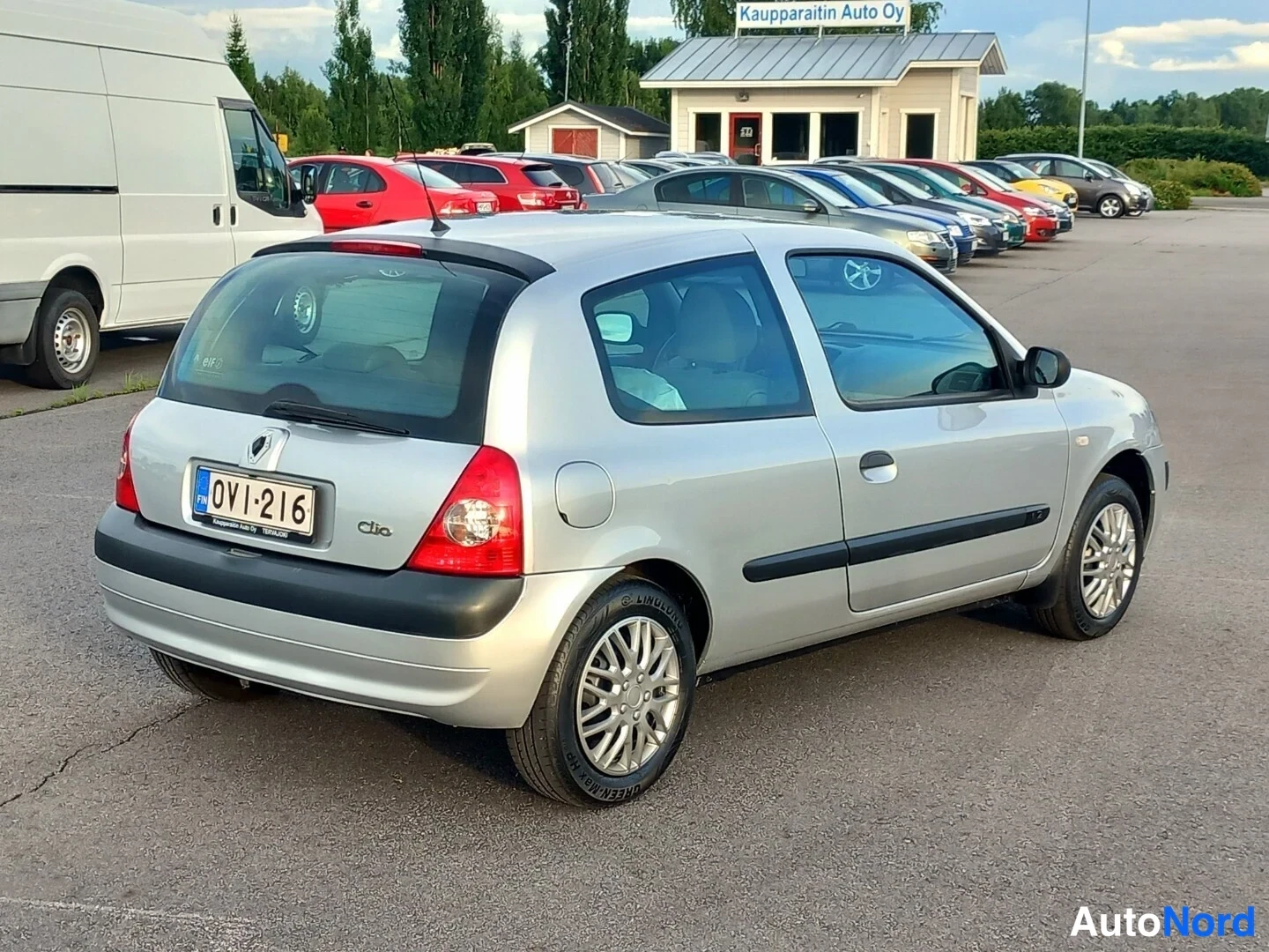 Takaviisto: Hopeanvärinen kolmioovinen Renault Clio takaa viistosti vasemmalta kuvattuna autopaikalla, rekisterikilpi.